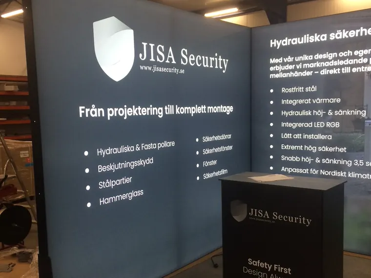 Krótsza ściana z logo JISA Security i lada z napisem Safety First