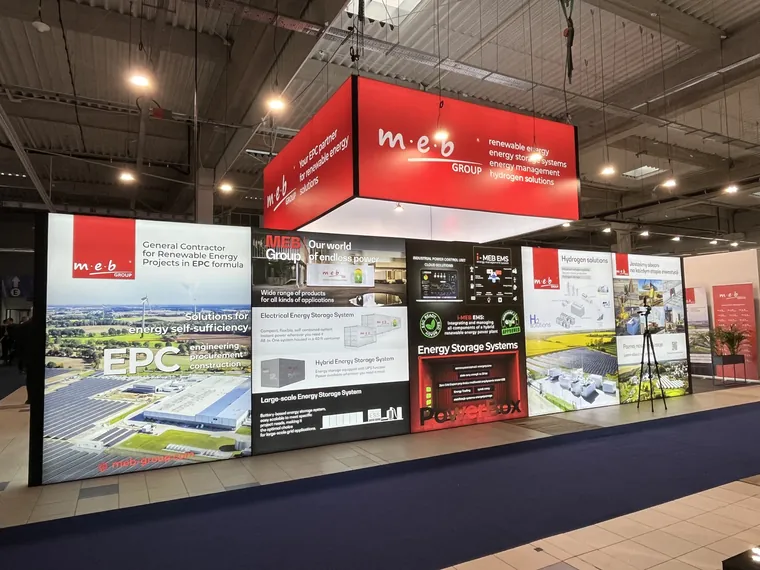 Długa podświetlana ściana z grafikami o magazynach energii i czerwone podwieszenie nad stoiskiem