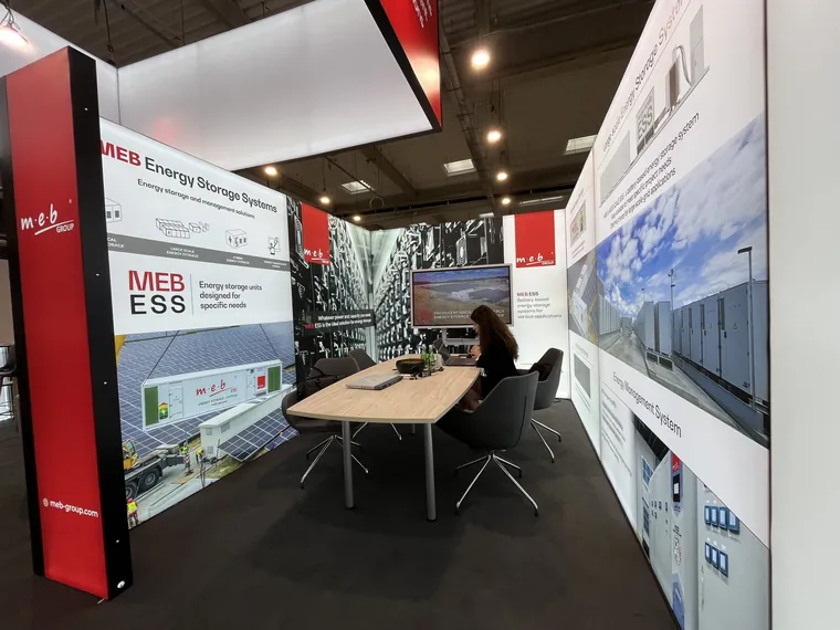 Zaplecze w środku stoiska: stół rozmów między podświetlanymi ścianami z grafiką MEB Energy Storage Systems