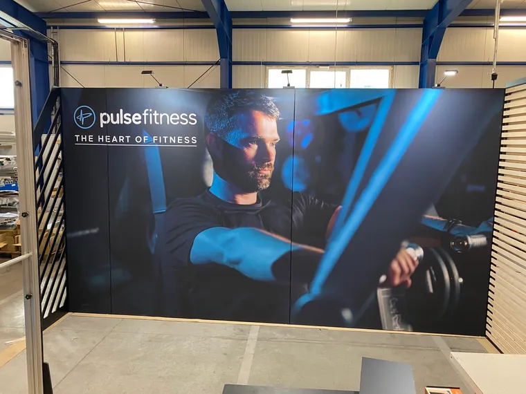 Ściana z dużym zdjęciem sportowca i hasłem The heart of fitness